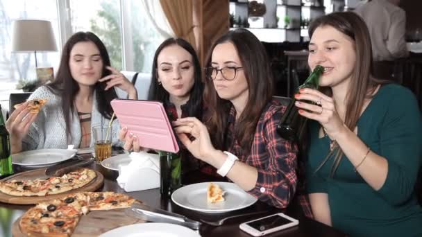 Несколько девушек едят пиццу и пьют пиво из бутылок в ресторане. Говорить смехом и праздновать — стоковое видео