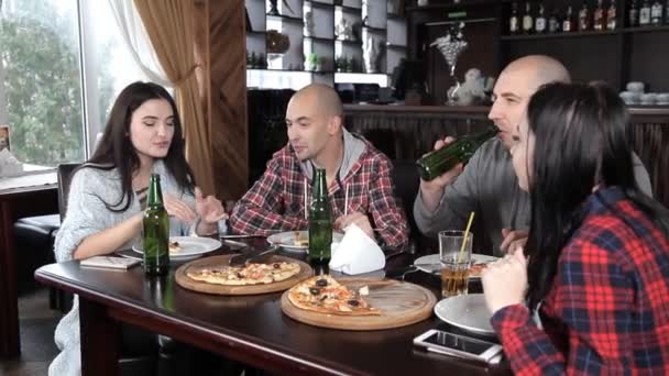 Bir grup genç insan bira içmek ve bir restoranda pizza yemek — Stok video
