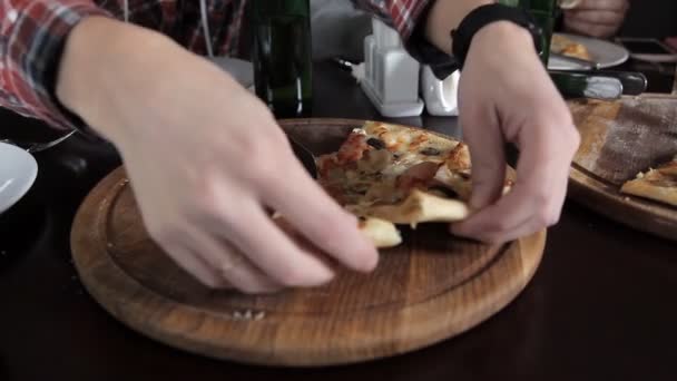 Een groep jonge mensen drinken bier en pizza eten in een restaurant — Stockvideo