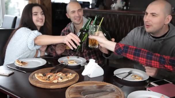 Un grupo de jóvenes bebe cerveza y come pizza en un restaurante — Vídeos de Stock