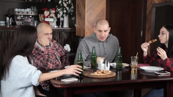 Een groep jonge mensen drinken bier en pizza eten in een restaurant — Stockvideo