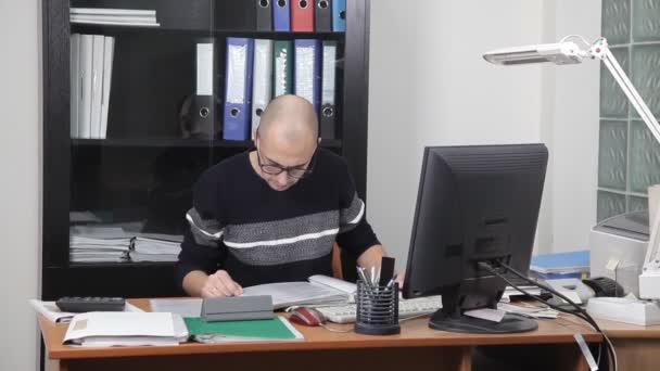 Un hombre que trabaja en la oficina en el lugar de trabajo. demasiado trabajo — Vídeo de stock