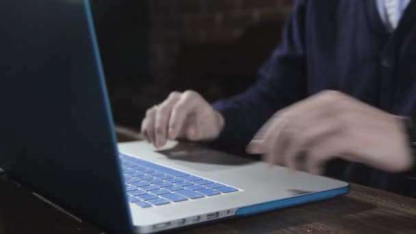 A writer writes a book novel on a laptop against a brick wall — Stock Video
