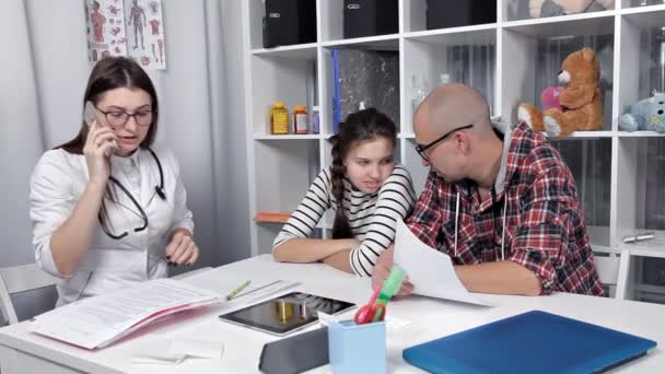 Papá y su hija vinieron a ver a un médico. El médico hace recomendaciones. Tratamiento — Vídeos de Stock