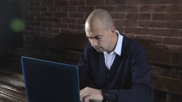 Pisarz pisze powieść książki na laptopa przed mur z cegły — Wideo stockowe