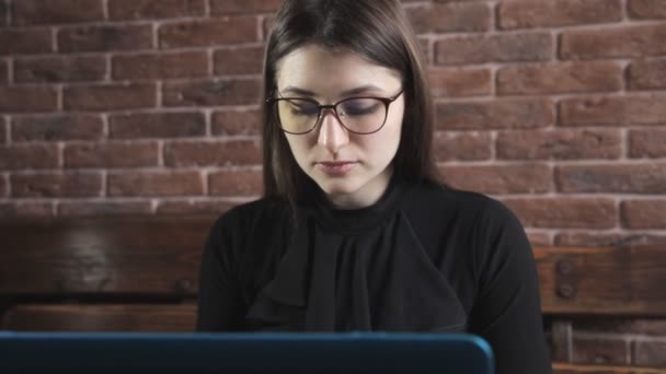 Pisarz pisze powieść książki na laptopa przed mur z cegły — Wideo stockowe