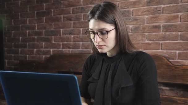 Pisarz pisze powieść książki na laptopa przed mur z cegły — Wideo stockowe