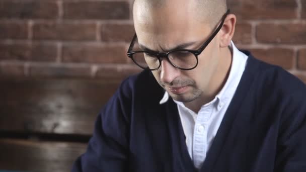 Een schrijver schrijft een boek-roman op een laptop tegen een bakstenen muur — Stockvideo