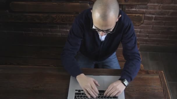 Een schrijver schrijft een boek-roman op een laptop tegen een bakstenen muur — Stockvideo
