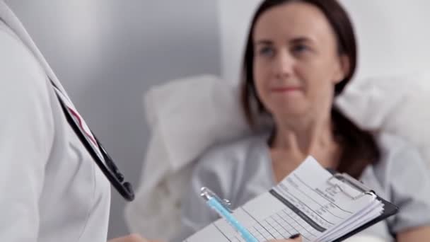 En läkare i patienter ward gör anteckningar om hans tillstånd av hälsa och behandling — Stockvideo