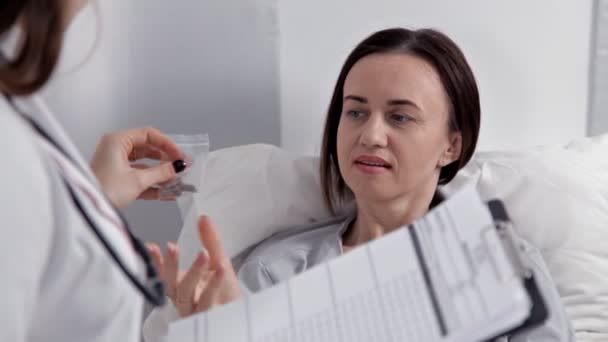 Bir doktor hasta koğuşunda sağlık ve tedavi onun durumuyla ilgili notlar yapıyor — Stok video