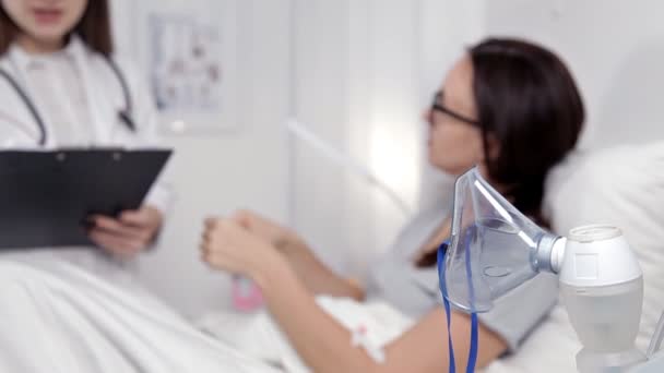 Den unge läkaren kommunicerar med patienten och gör lämpliga poster, förskrivning av läkemedel — Stockvideo