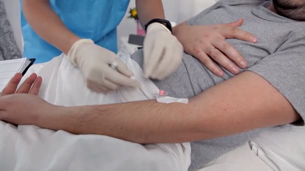 医生使用注射器给住院病人注射疫苗。该男子正在静脉注射毒品到手臂上治疗病人老人 — 图库视频影像