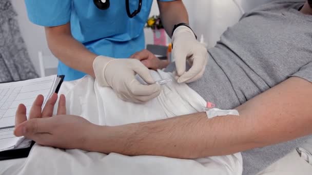 入院中の患者にワクチンの注射をする注射器を使用して医師。男が病気患者高齢者一人を癒すために腕に静脈内の薬剤注入です。 — ストック動画