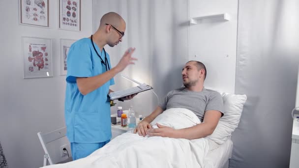 Врач дает пациенту лежащую в палате надежду на выздоровление — стоковое видео