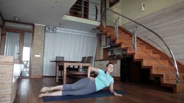 Mladá sportovní žena cvičit doma, dělá fitness cvičení na podlaze obývacího pokoje pomocí online osobní tréninkový program, dělá jógu pilates doma