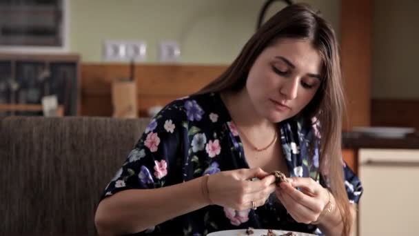 Uma jovem se senta na cozinha em sua casa e come — Vídeo de Stock