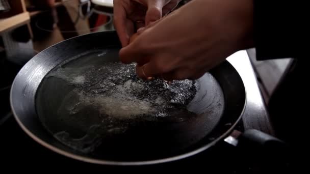 早上, 女孩在家里的厨房里准备早餐, 在煎锅里打破鸡蛋。特写。在家厨房煮鸡蛋 — 图库视频影像