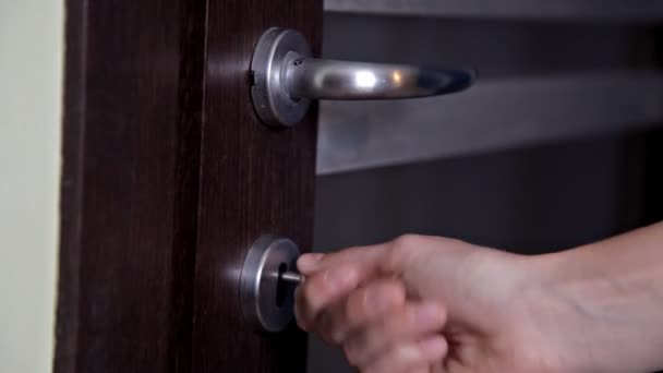 The girl opens and closes the door to the apartment. The person using the key and locking the door of the apartment — Stockvideo