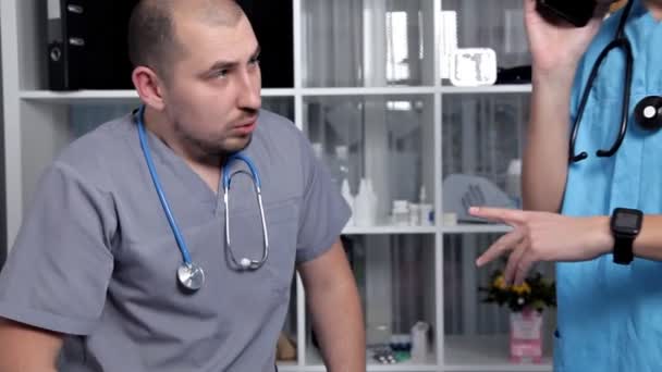 Erkek doktor ve yeni tıbbi Araştırmaları hakkında konuşmak iyi bir ruh hali içinde genç stajyer — Stok video