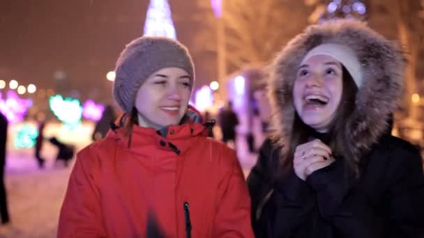 Les jeunes filles marchent en hiver sur la place centrale de la ville près du sapin de Noël. Vacances, neige, joie — Video