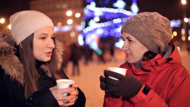 Jonge meisjes zijn drinken koffie in het park, lachen. Winterweer buiten. Koffiepauze. Kerst — Stockvideo