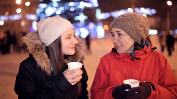 Las chicas jóvenes están tomando café en el parque, riéndose. El clima invernal afuera. Descanso. Navidad — Vídeos de Stock