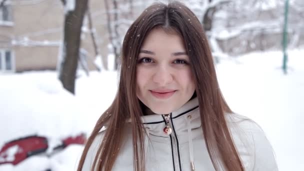 Een jong meisje poseert voor de camera op een koude winterdag. Sneeuw koude — Stockvideo