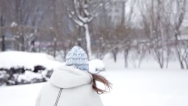 Kışın soğuk karda oynarken parkta genç neşeli kız yürüyor — Stok video