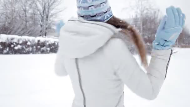 Joven chica alegre camina en el invierno en el parque, jugando en la nieve, frío — Vídeos de Stock