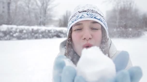 Una joven se regocija en el clima invernal y juega bolas de nieve en el parque — Vídeos de Stock