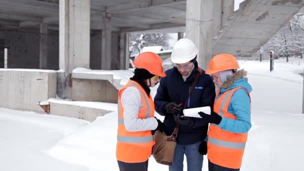 Duas mulheres inspetoras e arquitetas discutem com o engenheiro-chefe sobre o projeto de construção — Vídeo de Stock