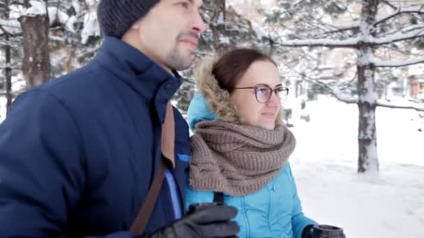 Twee jonge mensen elkaar ontmoeten in een romantische besneeuwde sfeer in de frisse lucht, drinken koffie en kus — Stockvideo