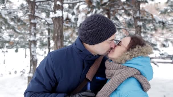 Due giovani si incontrano in una romantica atmosfera innevata all'aria aperta, bevono caffè e si baciano — Video Stock