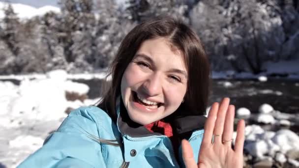 A menina perto do rio da montanha na floresta de inverno falando no vídeo usando um telefone celular — Vídeo de Stock