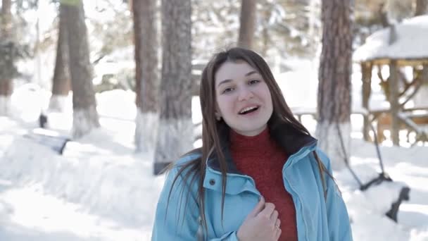 Una joven camina en el invierno en el bosque y posa para la cámara — Vídeo de stock