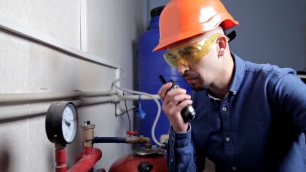 An engineer in glasses works in the boiler room, checks the maintenance of the heating system equipment — Stock Footage An engineer in glasses works in the boiler room, checks the maintenance of the heating system equipment Stock Video