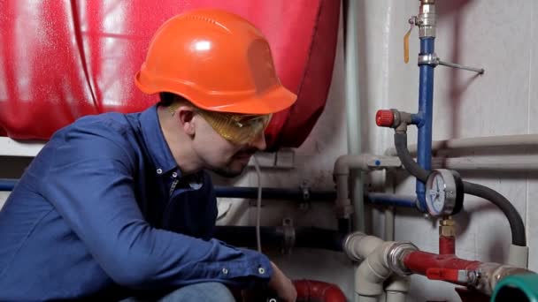 An engineer in glasses works in the boiler room, checks the maintenance of the heating system equipment — Stock Footage An engineer in glasses works in the boiler room, checks the maintenance of the heating system equipment Video Clip