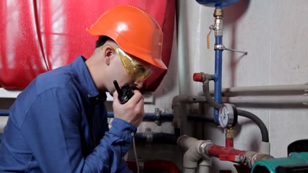 An engineer in glasses works in the boiler room, checks the maintenance of the heating system equipment — Stock Footage An engineer in glasses works in the boiler room, checks the maintenance of the heating system equipment Stock Footage