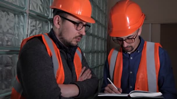 Два інженери обговорюють і роблять нотатки про завершену перевірку системи — стокове відео