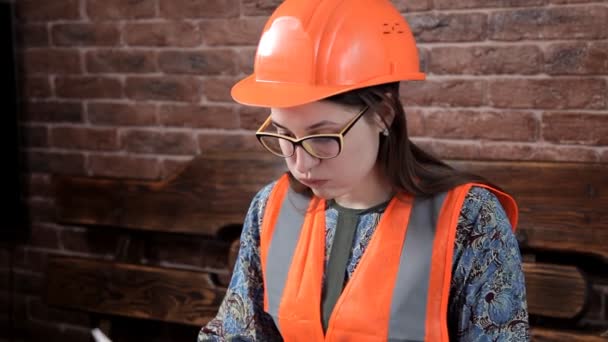 Junge Ingenieurin macht sich Notizen über die Arbeit. Spezialuniform und Helm — Stockvideo