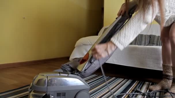A menina depois de limpar o apartamento, dobra o aspirador de pó — Vídeo de Stock
