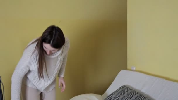 Young girl uses a vacuum cleaner to clean the dust in the pillow — Stock Video