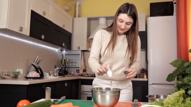 La chica preparó una ensalada de verduras y sal se vierte en ella — Vídeo de stock