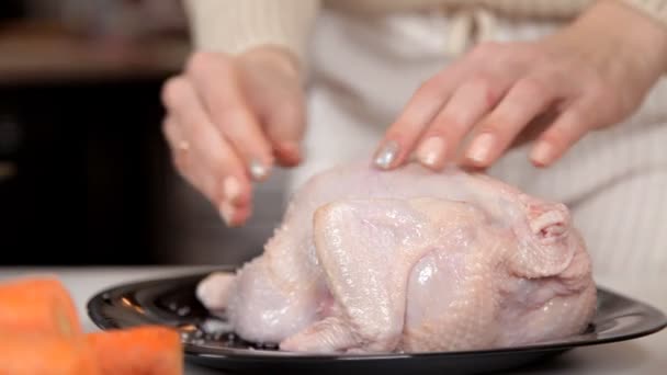 Uma jovem na cozinha está cozinhando frango, esfregando-o com especiarias. Jantar — Vídeo de Stock