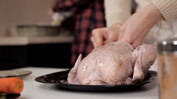 Dos chicas jóvenes en la cocina cocinan pollo, lo frotan con especias — Vídeos de Stock