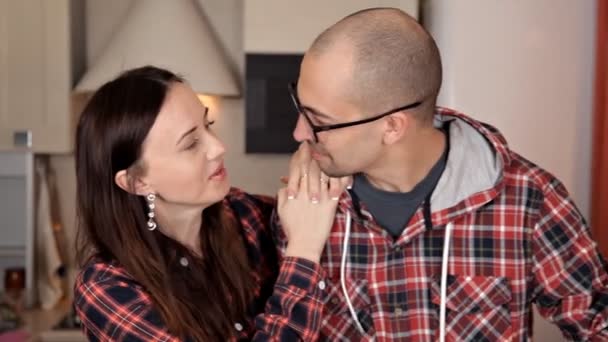 Hermosa pareja joven se alimenta mutuamente y sonríe mientras cocina en la cocina en casa — Vídeo de stock