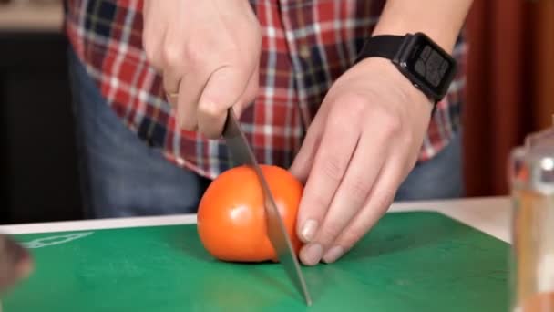 Flickan skär en tomat för sallad. Matlagning hemma — Stockvideo