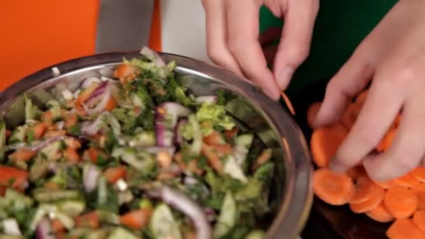 Het meisje zet wortelen in de salade. Thuis koken — Stockvideo