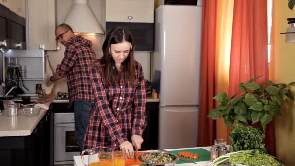 Bella giovane coppia si nutre a vicenda e sorride mentre cucina in cucina a casa — Video Stock